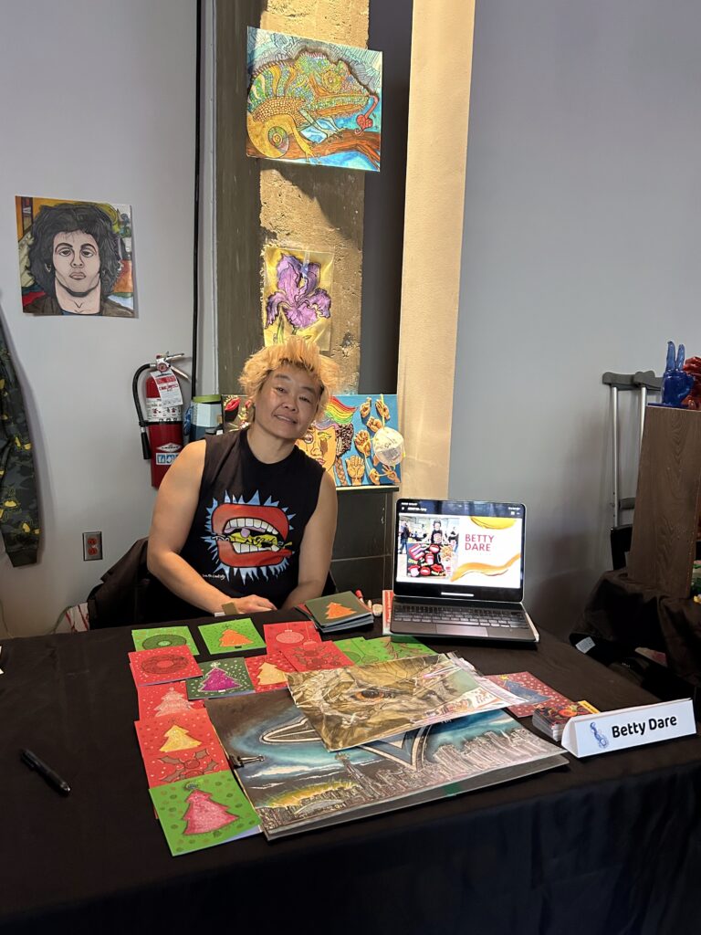 Betty Dare's booth with paintings climbing up the wall behind.